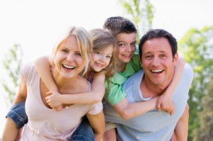 Couple giving two young children piggyback rides smiling Family Bail Bonds